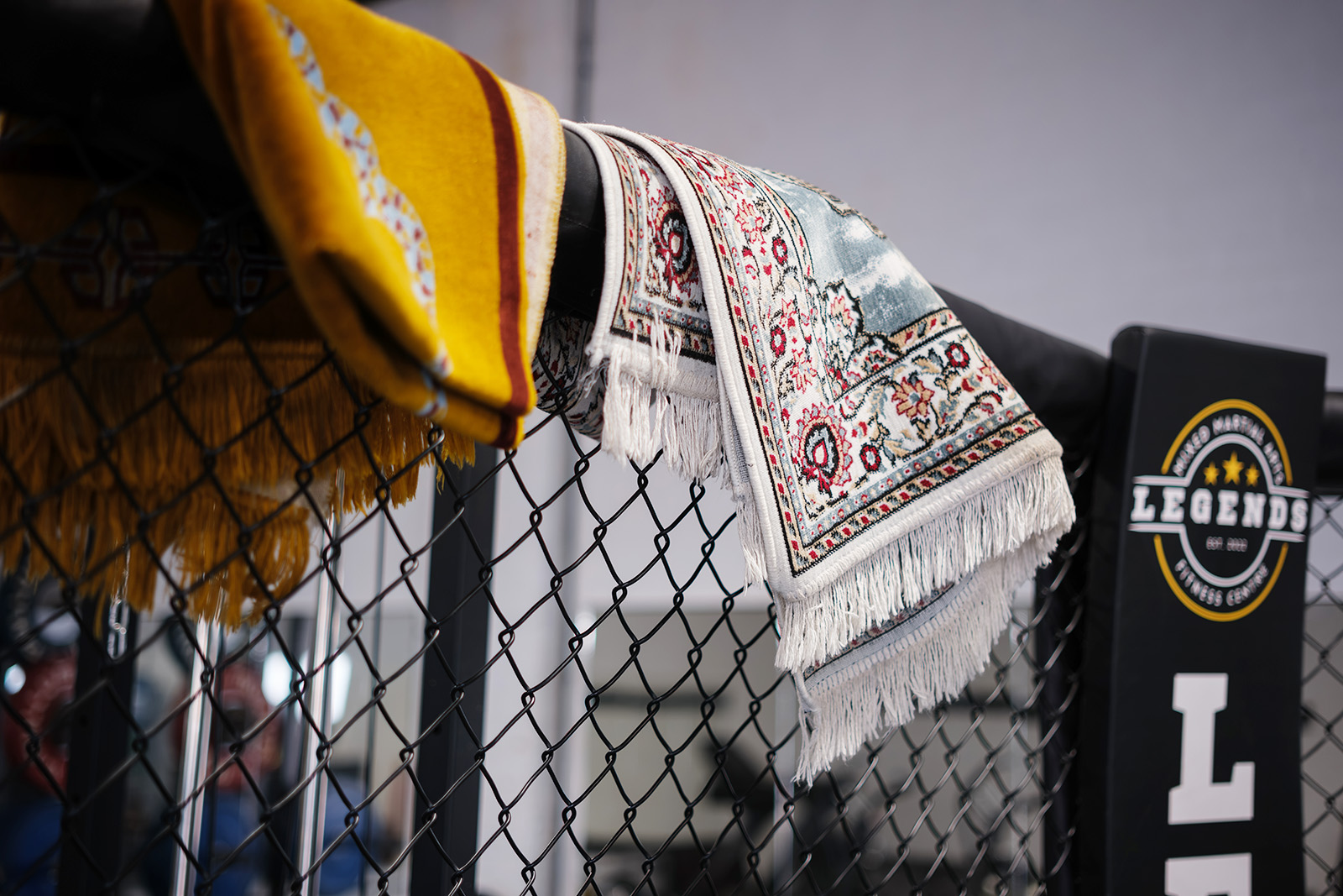 Prayer mats hanging over a cage fence at Legends Legends MMA and Fitness Centre, Luton