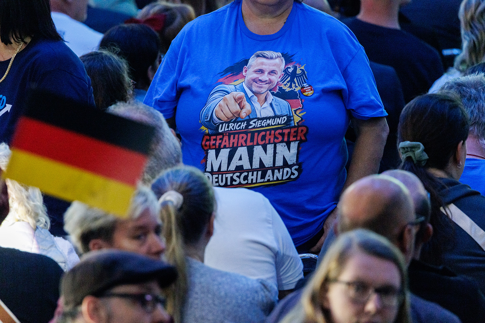 A photograph of AfD supporters attending a final campaign rally in Magdeburg on Saturday 5 September, 2026, the eve of the Saxony-Anhalt state elections. One is wearing a bright blue T-shirt with an image of Ulrich Siegmund, the AfD leader in the German state, pointing a finger above a slogan in German that translate as: 'Ulrich Siegmund The most dangerous man in Germany'