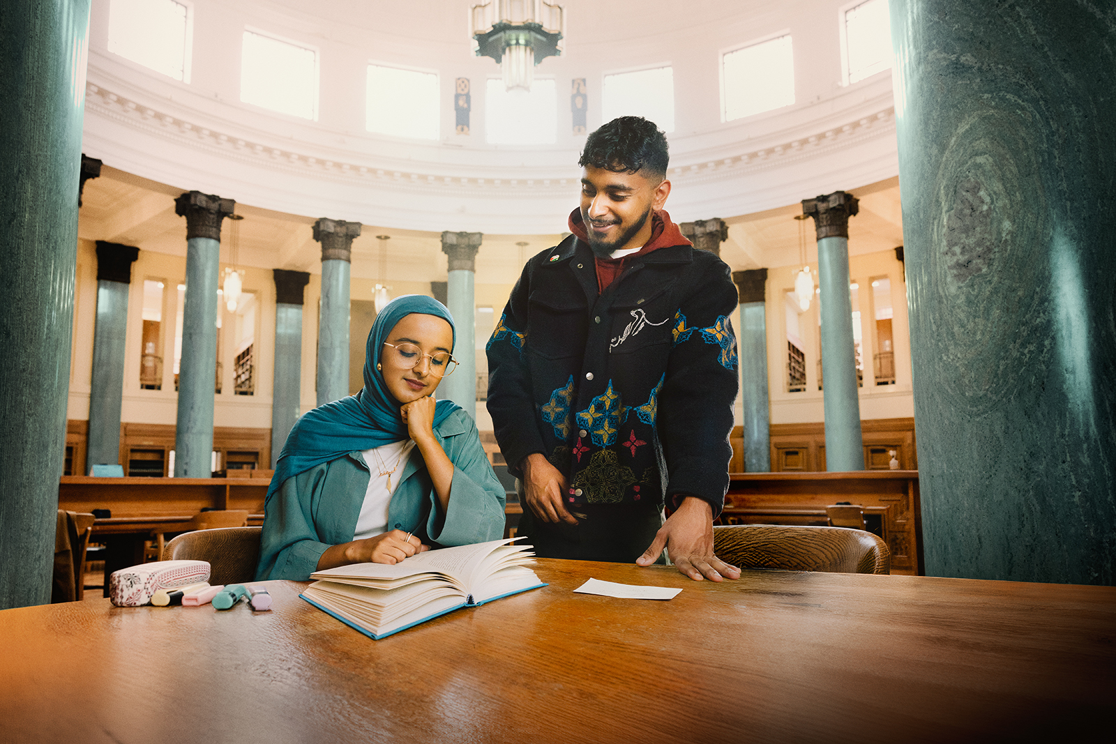 A promotional photograph of Suhaiymah Manzoor-Khan's Peanut Butter & Blueberries, featuring Humera Syed as Hafsah and Kashif Ghole as Bilal, in what looks like a university library setting
