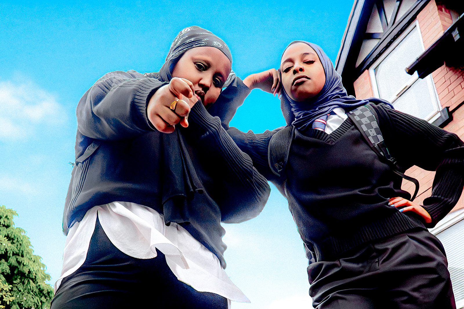 A promotional photograph for Fatima Ali Omar's play Off-Key, with a low angle shot of two Muslim girls in school uniform striking defiant poses
