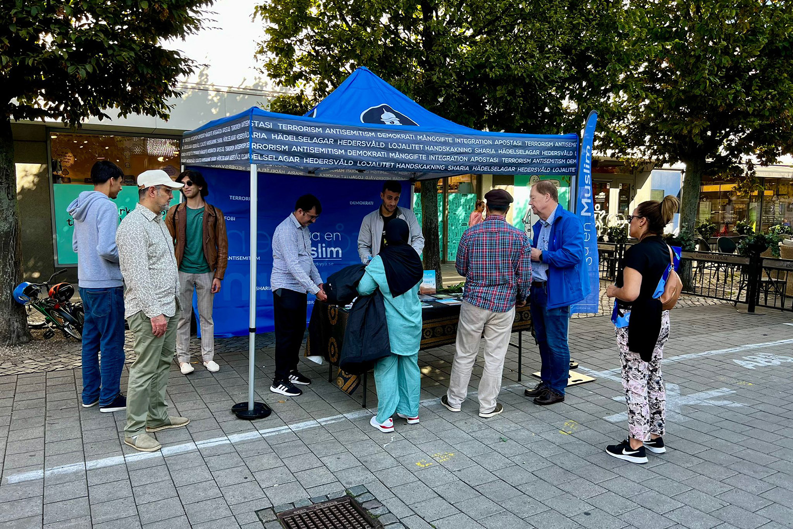 Volunteers speak to passersby at the Fråga en Muslim (Ask A Muslim) stand in a pedestrianised shopping street