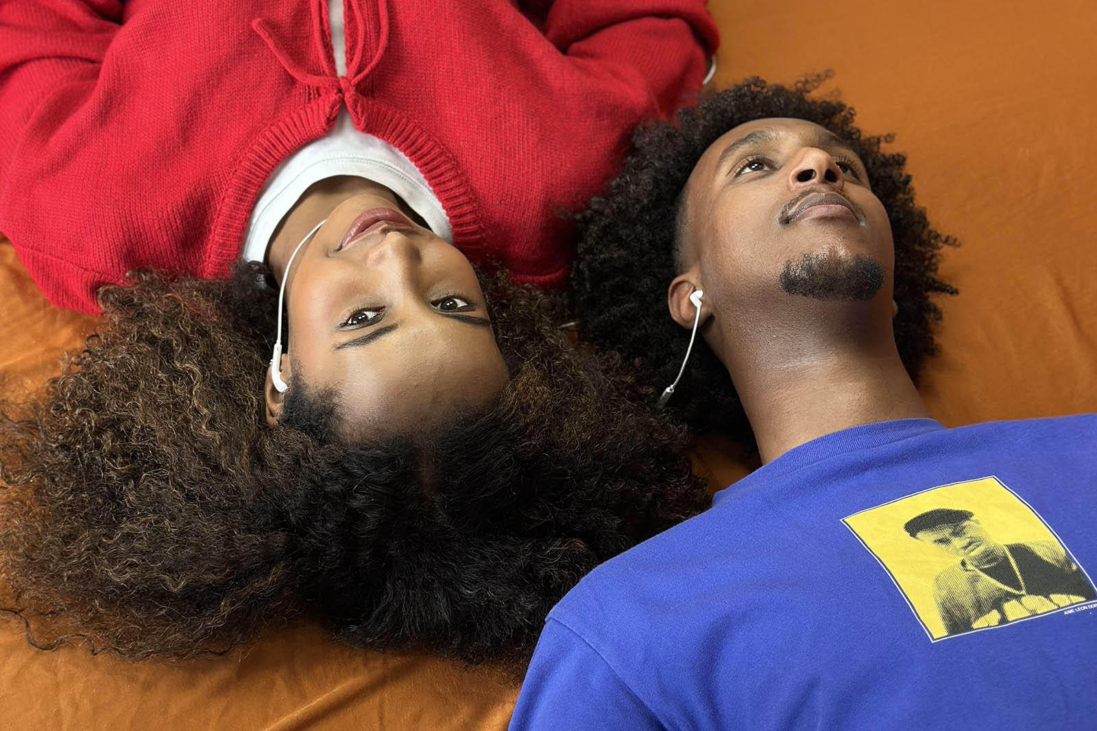 A close-up photograph of Hadsan Mohamud and Mohamed Hashif's characters in Mohamud’s play Crush, lying down close together and sharing headphones