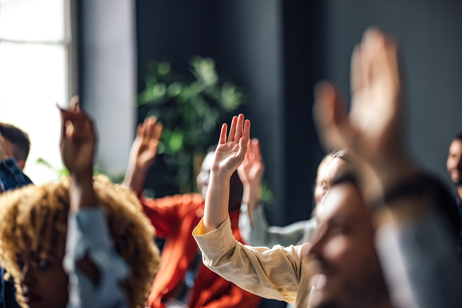 A stock image of a group of people sitting in a seminar with one arm raised
