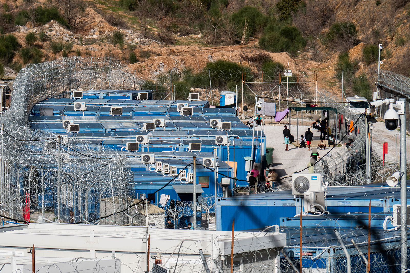 corrugated iron containers and portaloos surrounded by barbed wire
