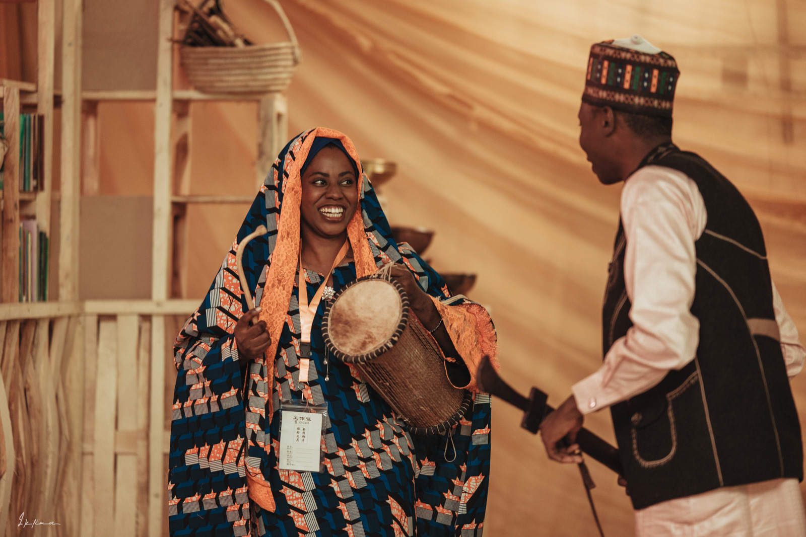 A photograph of Habiba Malumfashi, Hibaf's logistics manager, performing on stage with a drum