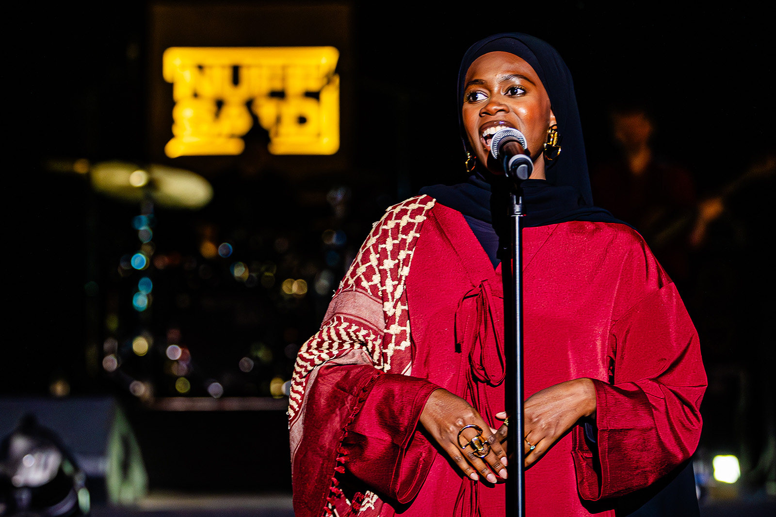 A photograph of poet Rakaya Fetuga on stage performing