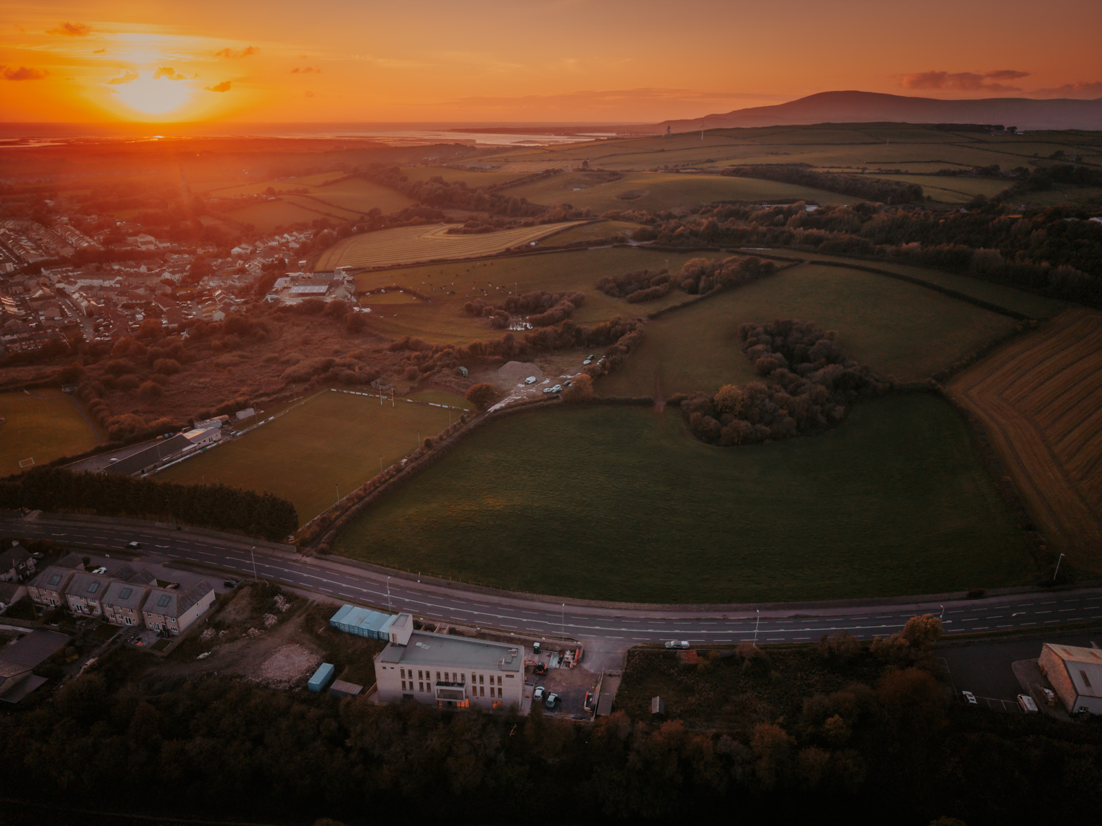 A photograph giving an aerial view of the South Lakes Islamic Centre site, with the sun about to set to the west