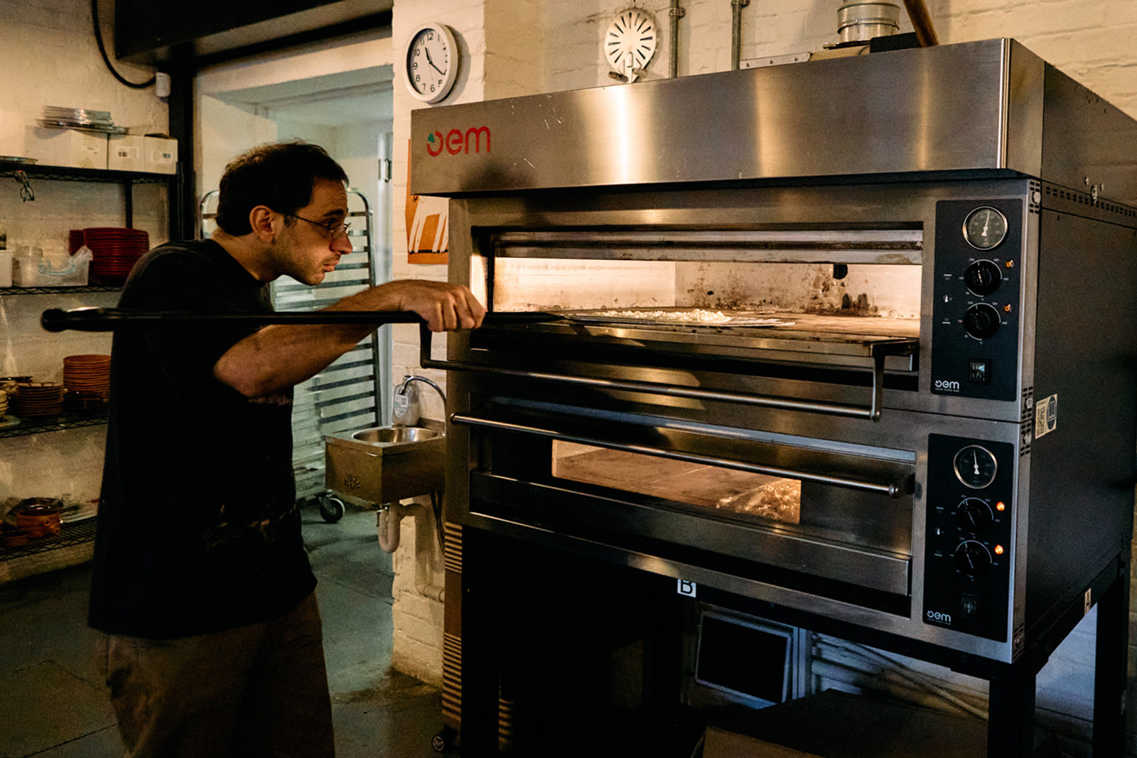 A photograph of Edami co-founder Minas Missirian cooking a flatbread in an oven similar to those used for pizza. The bakery uses this rather than a domed metal griddle, or saj, that's more traditionally used to cook Lebanese flatbread